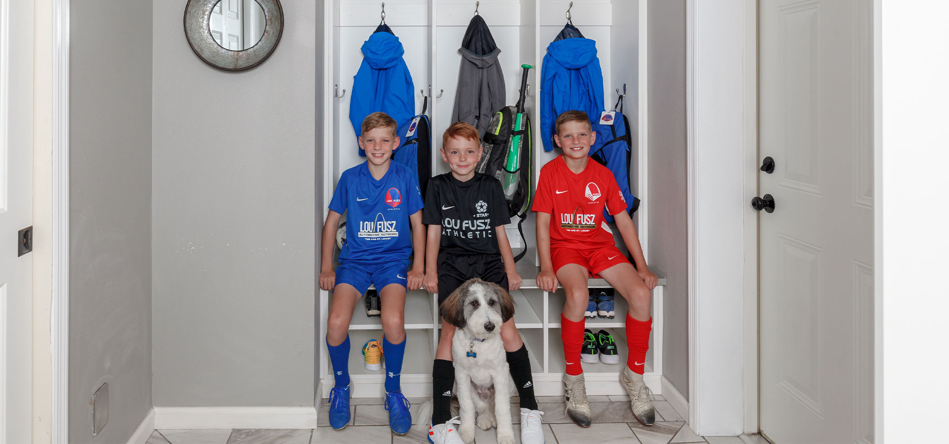 Mudroom lockers with children in soccer jerseys sitting on the bench