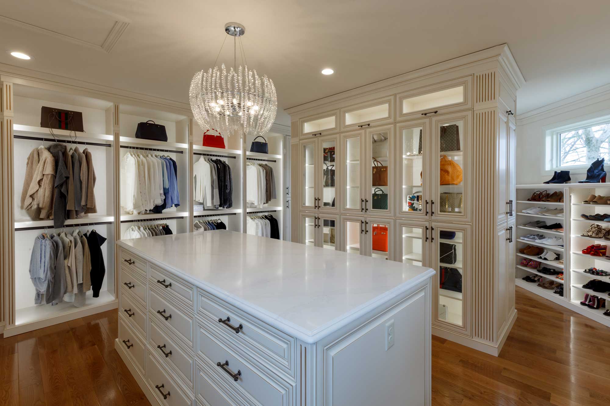 Walk-in closet with extensive shelving surrounding a purse display case